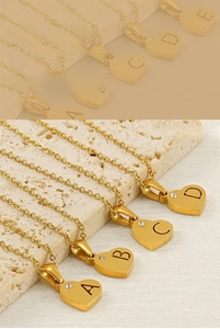 Détail de pendentifs cœur dorés avec lettres gravées et petits accents de diamants