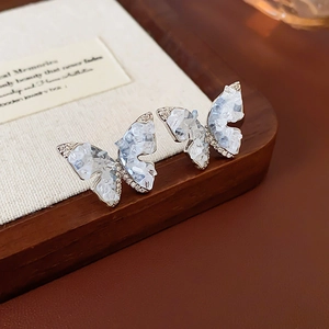 Gros plan détaillé de boucles d'oreilles papillon avec pierre bleu clair et zircons