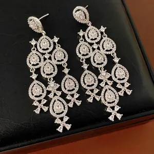 Elegante silberne Ohrringe mit Zirkonia-Blumen-Quasten auf schwarzem strukturiertem Hintergrund