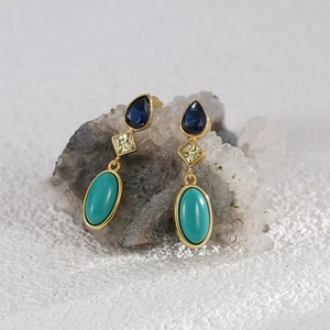 Detailed macro view of three-tier gold earrings with teardrop blue zircons on crystal stones