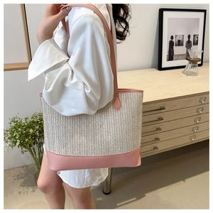 Close-up of woven tote bag with pink leather straps worn on shoulder in a home setting