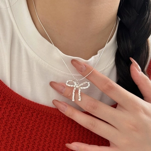 Minimalist 925 sterling silver bow necklace with woven texture worn on a person