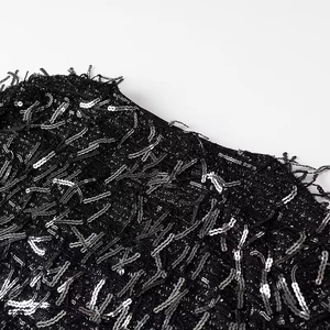 Detailed macro view of black sequins and fringe embellishment on a mini dress