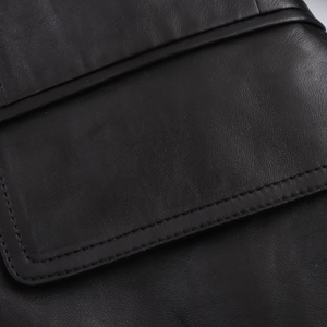 Close-up of black PU leather jacket featuring detailed flap pocket and double stitching