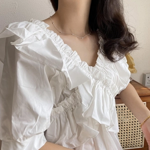 Detail of white V-neck ruffled blouse paired with minimalist olive bead silver necklace