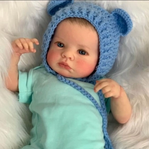 Realistic 49cm Loulou Awake newborn reborn doll in blue knit hat on plush white blanket