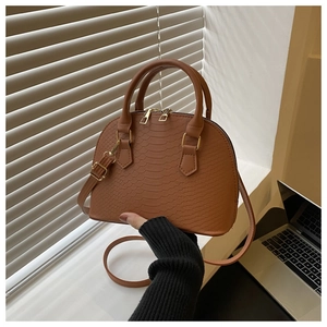 Close-up of brown crocodile embossed shell bag with golden hardware and double handles
