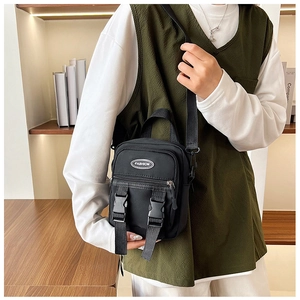 Dettaglio della borsa a tracolla in nylon nero con doppie fibbie ed etichetta moda sul davanti