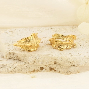 Golden irregular pleated C-shaped stainless steel earrings on natural stone surface