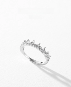 Macro shot of silver S925 crown ring with micro-pave zirconia on a white textured surface