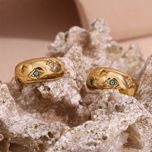Detail of 18K gold-plated star and moon earrings with colorful zircon on a coral stone