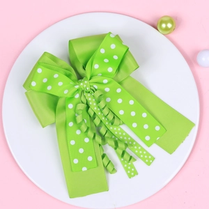 Detail of green polka dot ribbon hair bow with curly streamers on a decorative tray