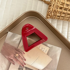 Close-up of a premium red hollow acetate hair claw clip on a golden tray display