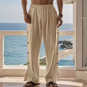 Detail of linen pants featuring side buttons and drawstring waist in a coastal setting