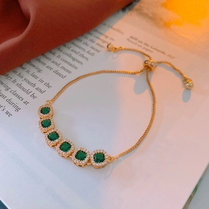 Detail of adjustable gold bracelet featuring a square green zircon set on vintage silk