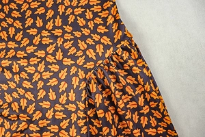 Detailed view of deep blue fabric featuring orange leaf prints and pleated stitching