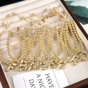Detailed row of gold bead bracelets with sparkling cubic zirconia initial letter charms