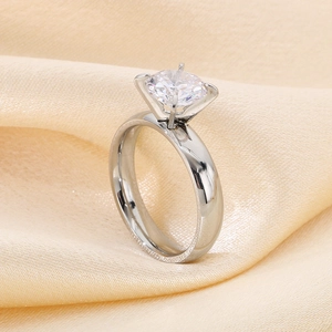 Side view of a silver six-claw solitaire ring on champagne silk fabric background
