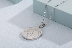 Macro detail of silver stainless steel circular pendant with occult Samael engraving