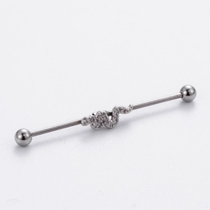 Macro detail of silver industrial barbell piercing featuring a crystal-studded snake design