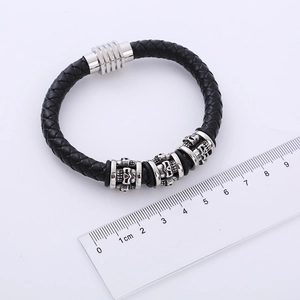 Macro detail of men's leather bracelet with steel skulls and magnetic clasp