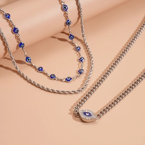 Detail of silver necklaces with crystal-encrusted evil eye charms and beaded chains