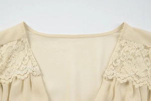 Macro detail of the beige chiffon top neckline featuring delicate floral lace embroidery