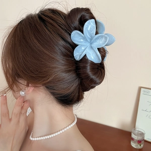 Détail de la pince à cheveux fleur en acrylique bleu marbré portée par un modèle