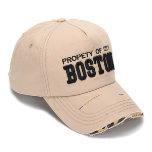 Macro detail of beige baseball cap featuring Boston embroidery and distressed camo brim