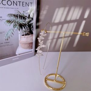 Detail of a golden headband with sparkling rhinestone butterfly on a gold display stand