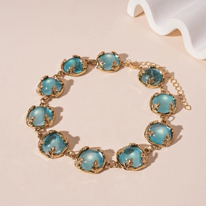 Detail of vintage golden link bracelet with blue resin stones and leaf-shaped settings