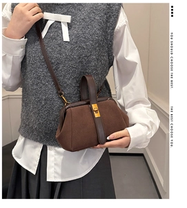 Brown vintage shell-shaped handbag with suede texture and gold lock shown on a model