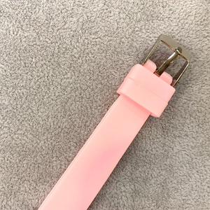 Detail of pink soft silicone watch band with a silver metal buckle on gray texture