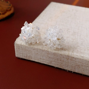 Macro shot of cluster bead earrings with transparent faceted glass on linen box