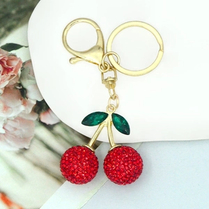 Macro shot of red rhinestone cherry keychain with green leaves and gold lobster clasp