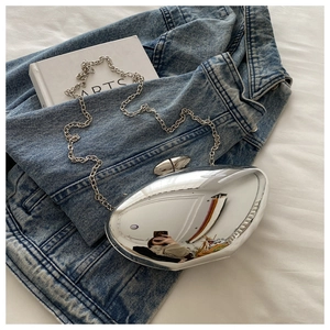 Chic silver pebble-shaped acrylic crossbody bag with chain on denim background