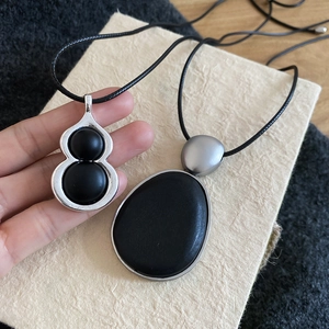 Gros plan du pendentif gourde minimaliste en argent avec perles noires et cordon tressé