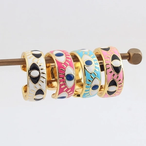 Detail of four colorful evil eye rings in gold plating with enamel finish on a rack