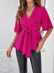 Détail du haut rose fuchsia à col en V avec taille croisée et tissu drapé élégant