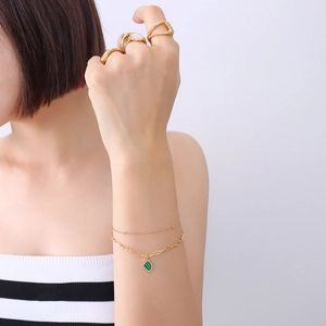 Double-layered gold chain bracelet with geometric emerald pendant and matching ring set