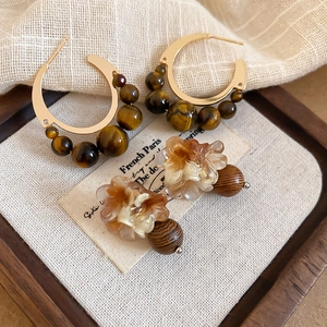 Détail macro de boucles d'oreilles rétro en résine avec perles en bois et oeil-de-tigre