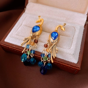 Detailed macro shot of vintage peacock crystal earrings in a brown leather jewelry box