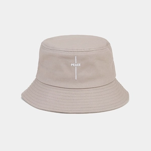 Detailed view of PEACE embroidery on a beige cotton bucket hat with clean stitching
