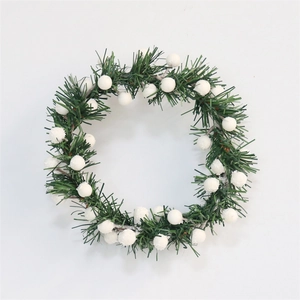 Close-up of green pine needles and white berry clusters on a Christmas candle ring wreath