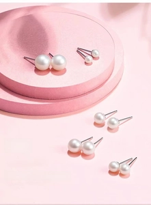 Detailed comparison of five sizes of classic white pearl stud earrings on a pink pedestal