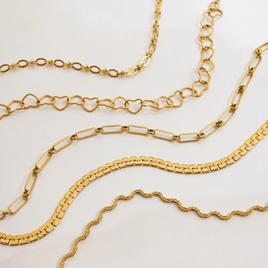 Set of five gold titanium steel snake and paperclip link necklaces on white background