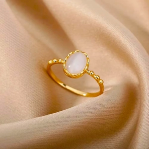 Detail of vintage gold ring with oval white gemstone on elegant champagne silk