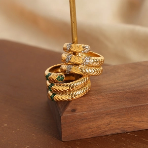 Goldener Schichtring im Schlangendesign mit grünen Kristallen und Weizenmuster