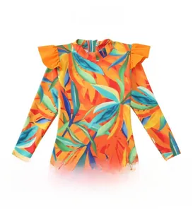 Detail of girls long sleeve swimsuit with tropical palm leaf print and orange ruffles