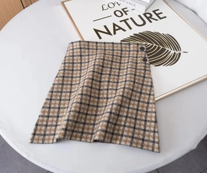 Détail de la jupe trapèze à carreaux marron avec boutons décoratifs en laine mélangée